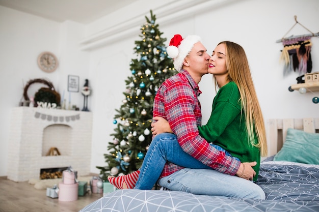 Padres enamorados en la cama en navidad