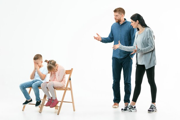 Padres enojados regañando a sus hijos, hijo e hija en casa. Foto de estudio de familia emocional. Las emociones humanas, la infancia, los problemas, los conflictos, la vida doméstica, el concepto de relación