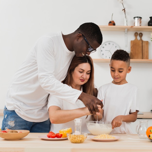Padres enseñando a hijo a preparar comida