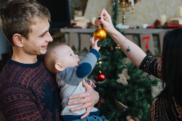 Foto gratuita padres enseñando a su bebe una bola de navidad