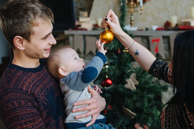 Padres enseñando a su bebe una bola de navidad