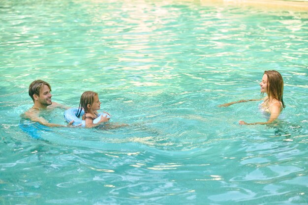 Padres enseñando a su hija a nadar y luciendo involucrados
