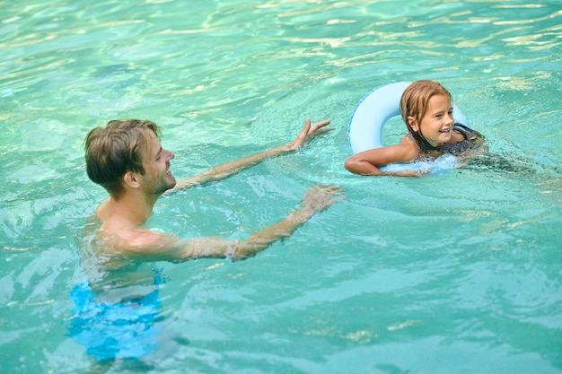 Padres enseñando a su hija a nadar y luciendo involucrados