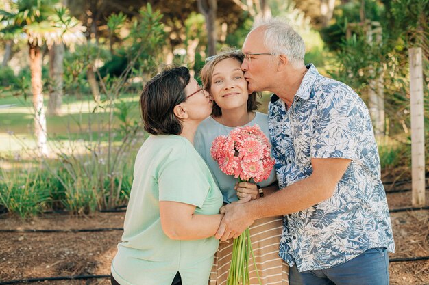 Padres felices besando a su hija adulta