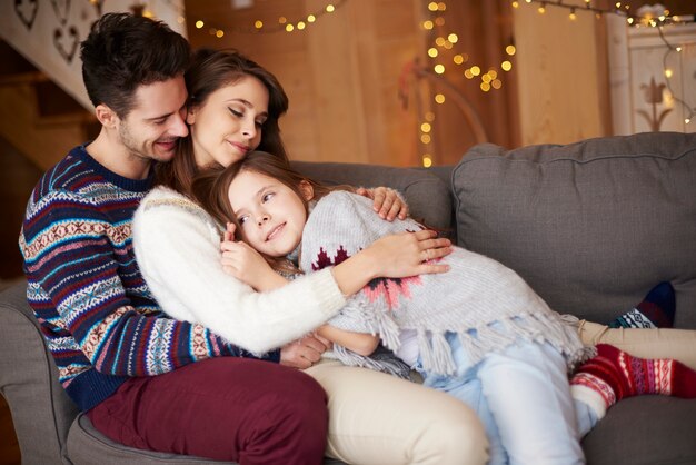 Padres felices con niña relajándose en el sofá