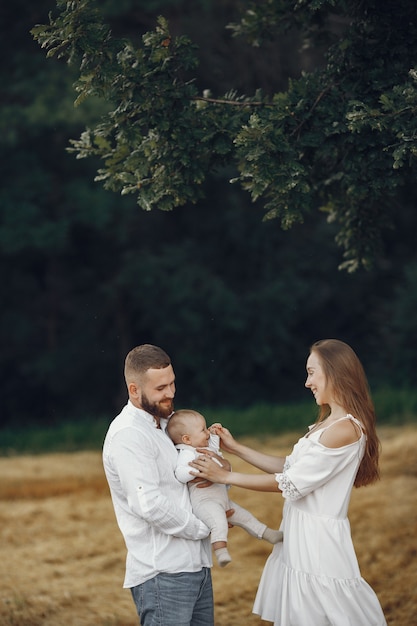 Padres con hija. Familia en un campo. Niña recién nacida. Mujer con un vestido blanco.