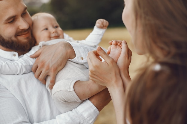 Padres con hija. Familia en un campo. Niña recién nacida. Mujer con un vestido blanco.