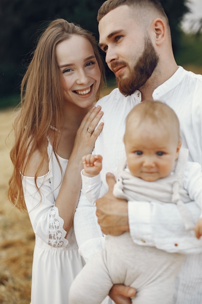 Padres con hija. Familia en un campo. Niña recién nacida. Mujer con un vestido blanco.