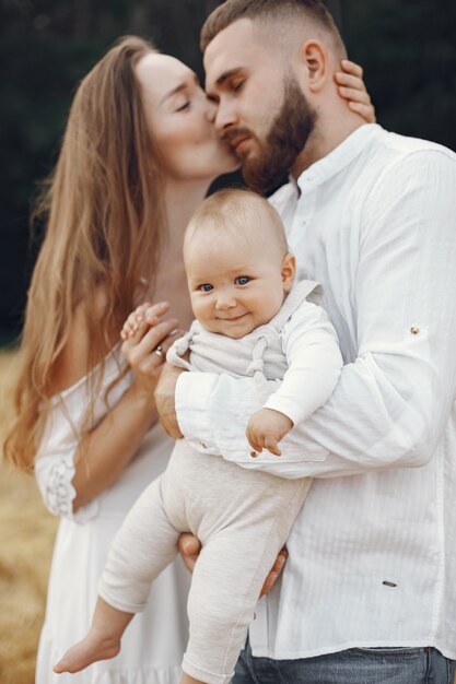 Padres con hija. Familia en un campo. Niña recién nacida. Mujer con un vestido blanco.