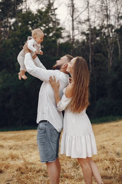 Padres con hija. Familia en un campo. Niña recién nacida. Mujer con un vestido blanco.