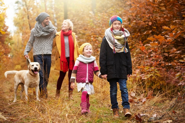 Padres con hijos caminando en el bosque de otoño