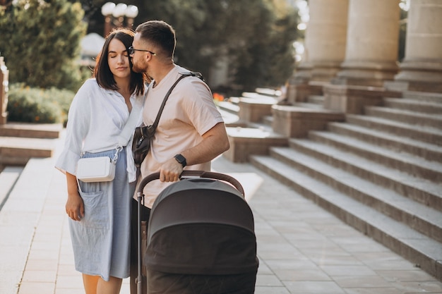 Los padres jóvenes caminando con su bebé en un cochecito