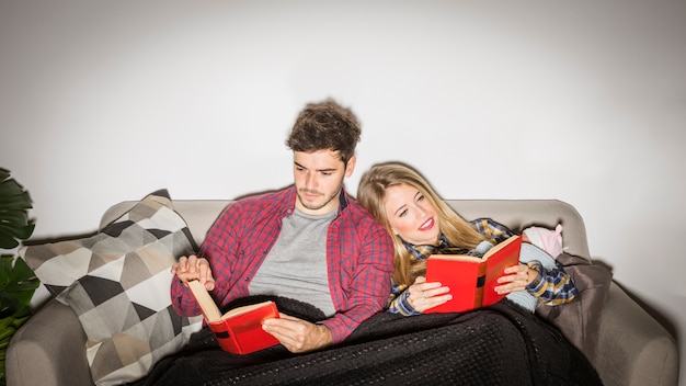 Foto gratuita padres jóvenes con libros de lectura para bebés