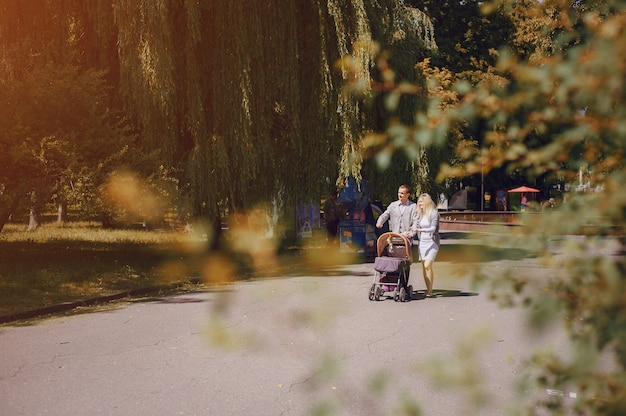 Foto gratuita padres jóvenes paseando con su bebé en un día soleado