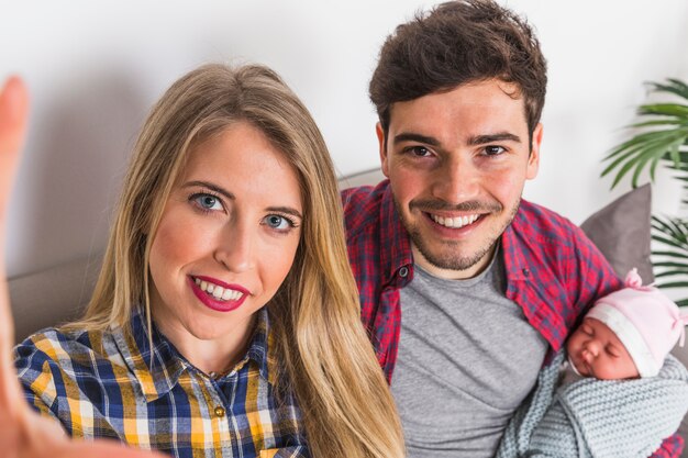 Padres jovenes que toman selfie con bebe