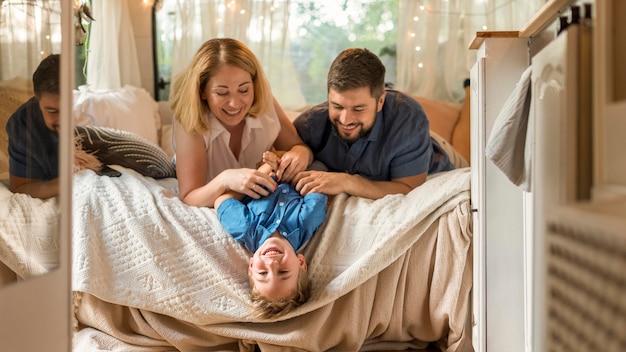 Foto gratuita padres jugando con su hijo en la cama de una caravana