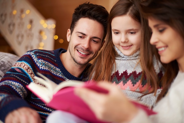 Padres leyendo el libro a su hija.