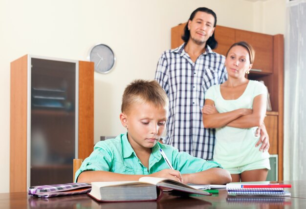 padres mirando a su hijo haciendo la tarea