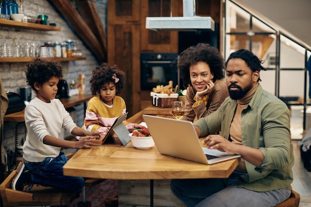 Padres negros y sus hijos usando tecnología inalámbrica en casa