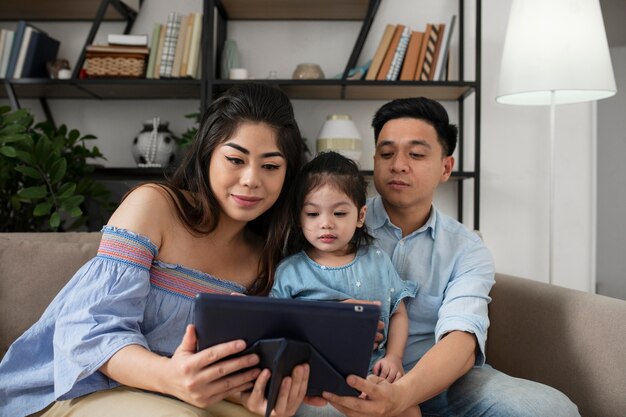 Padres y niña con tableta de tiro medio