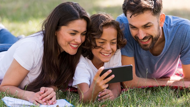 Los padres y el niño viendo algo en el teléfono inteligente en el parque