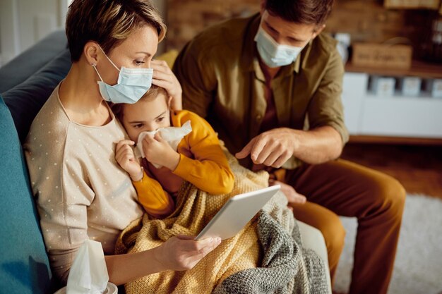 Padres preocupados con mascarillas hablando por videollamada con un médico sobre su hija enferma