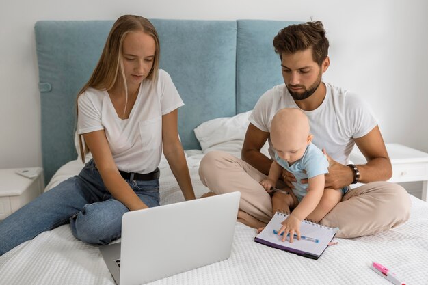 Padres que trabajan en la computadora portátil desde casa durante la cuarentena con el niño