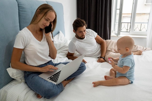 Foto gratuita padres que trabajan en la computadora portátil desde casa durante la cuarentena con el niño