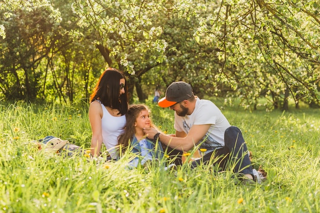 Padres sentados con hija en hierba verde