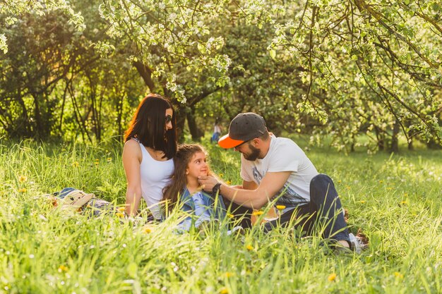 Padres sentados con hija en hierba verde