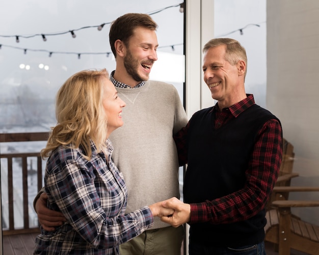 Padres sonrientes abrazando a hijo en casa