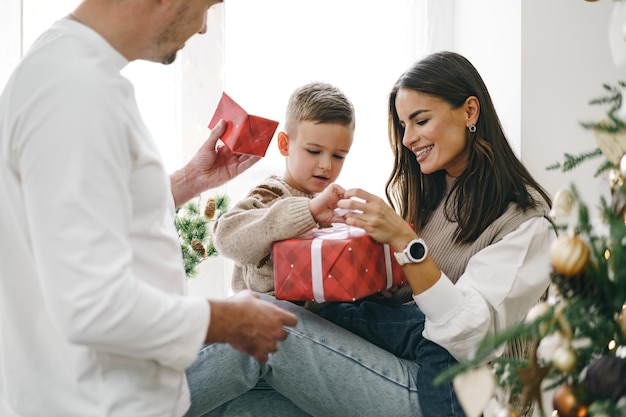 Padres sonrientes dando regalo de Navidad a su hijo en casa