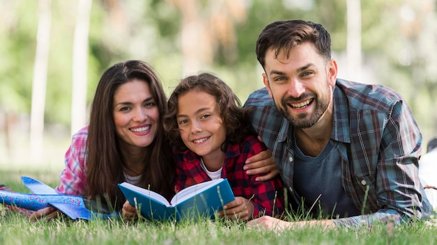 Padres sonrientes y niños leyendo mientras están juntos