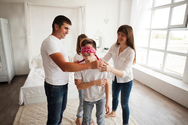 Padres sonrientes con sus hijos divirtiéndose en casa.