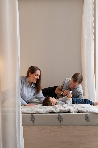 Padres sonrientes de tiro medio y niño en la cama