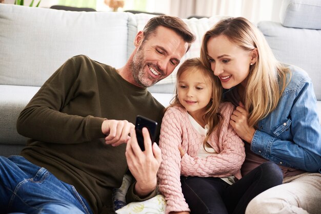 Los padres y su hija mirando el teléfono móvil