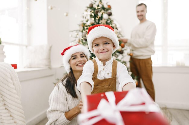 Los padres y su pequeño hijo se divierten y juegan juntos en el interior en la época navideña