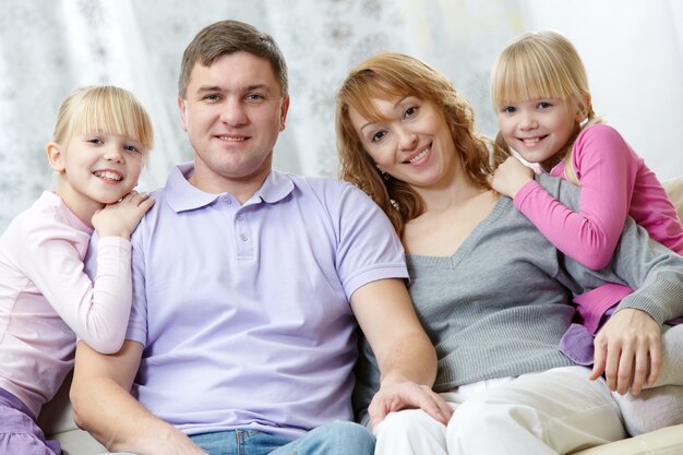 Padres con sus hijas sentados en el sofá