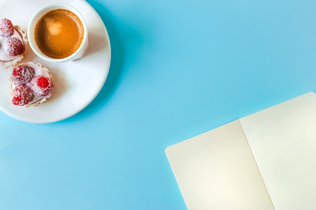 Página en blanco y tarta con vaso de café sobre fondo azul