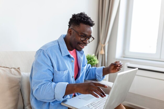 Pago en línea Joven con tarjeta de crédito y computadora portátil para compras en línea concepto de viernes negro o lunes cibernético Hombre pagando con tarjeta de crédito en la computadora portátil en la oficina en casa