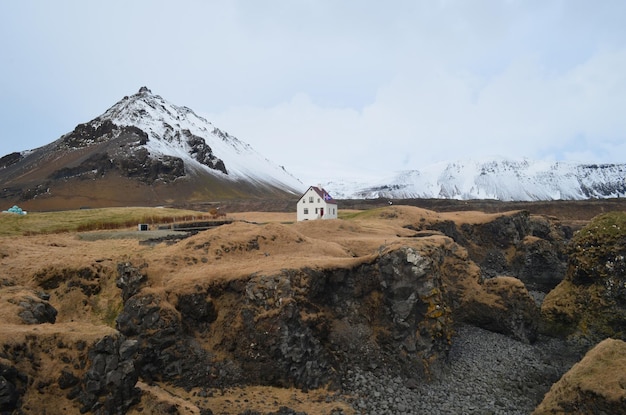 Un paisaje accidentado y montañas cubiertas de nieve rodean Hellnar Islandia.