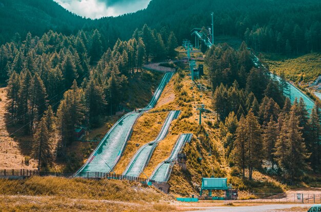 Paisaje de altas colinas cubiertas de alerces y senderos bajo cielo nublado en Pragelato, Italia