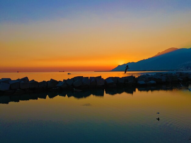 Paisaje de amanecer en una orilla del mar con una silueta de montañas