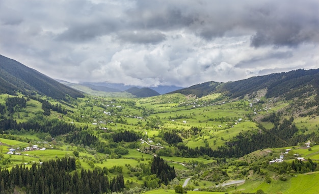 Paisaje de colinas cubiertas de edificios y bosques bajo un oscuro cielo nublado