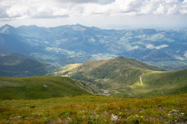 Paisaje de colinas cubiertas de hierba y árboles bajo un cielo nublado y la luz del sol durante el día