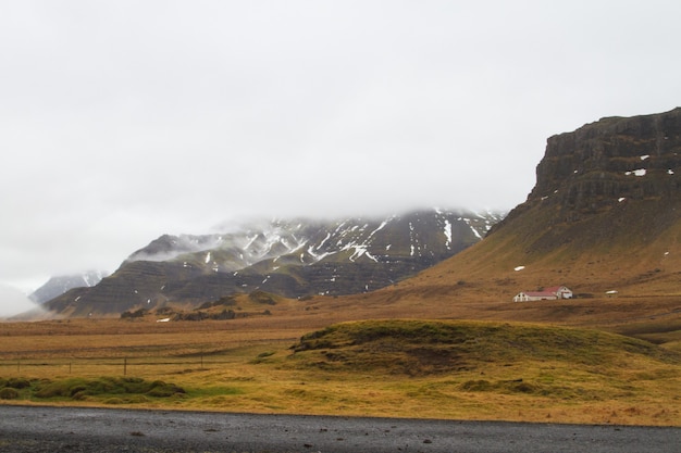 Paisaje de colinas cubiertas de nieve y hierba bajo un cielo nublado en Islandia