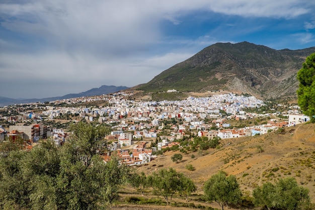 Paisaje de colinas cubiertas de vegetación y edificios bajo un cielo nublado y la luz del sol