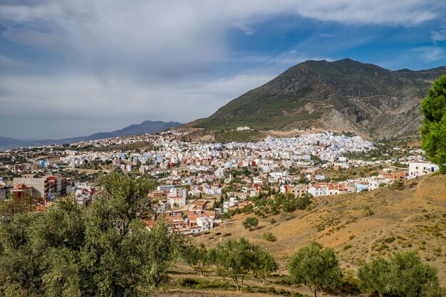 Paisaje de colinas cubiertas de vegetación y edificios bajo un cielo nublado y la luz del sol