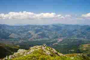 Foto gratuita paisaje de colinas cubiertas de vegetación con montañas rocosas bajo un cielo nublado en el