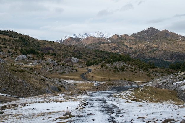 Foto gratuita paisaje con una gran cantidad de montañas rocosas cubiertas de nieve bajo un cielo nublado